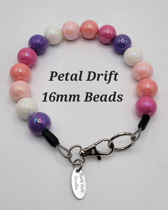 Petal Drift 16mm Beads, a collar of pink, purple, and white beads with a Bark Ave Studio tag