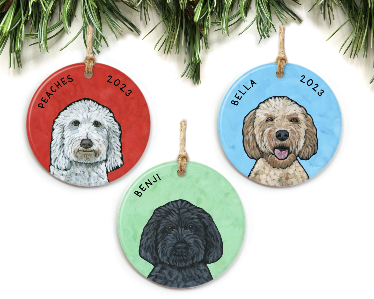 Three dog portrait ornaments hanging from pine branches. Peaches, Bella, and Benji are featured