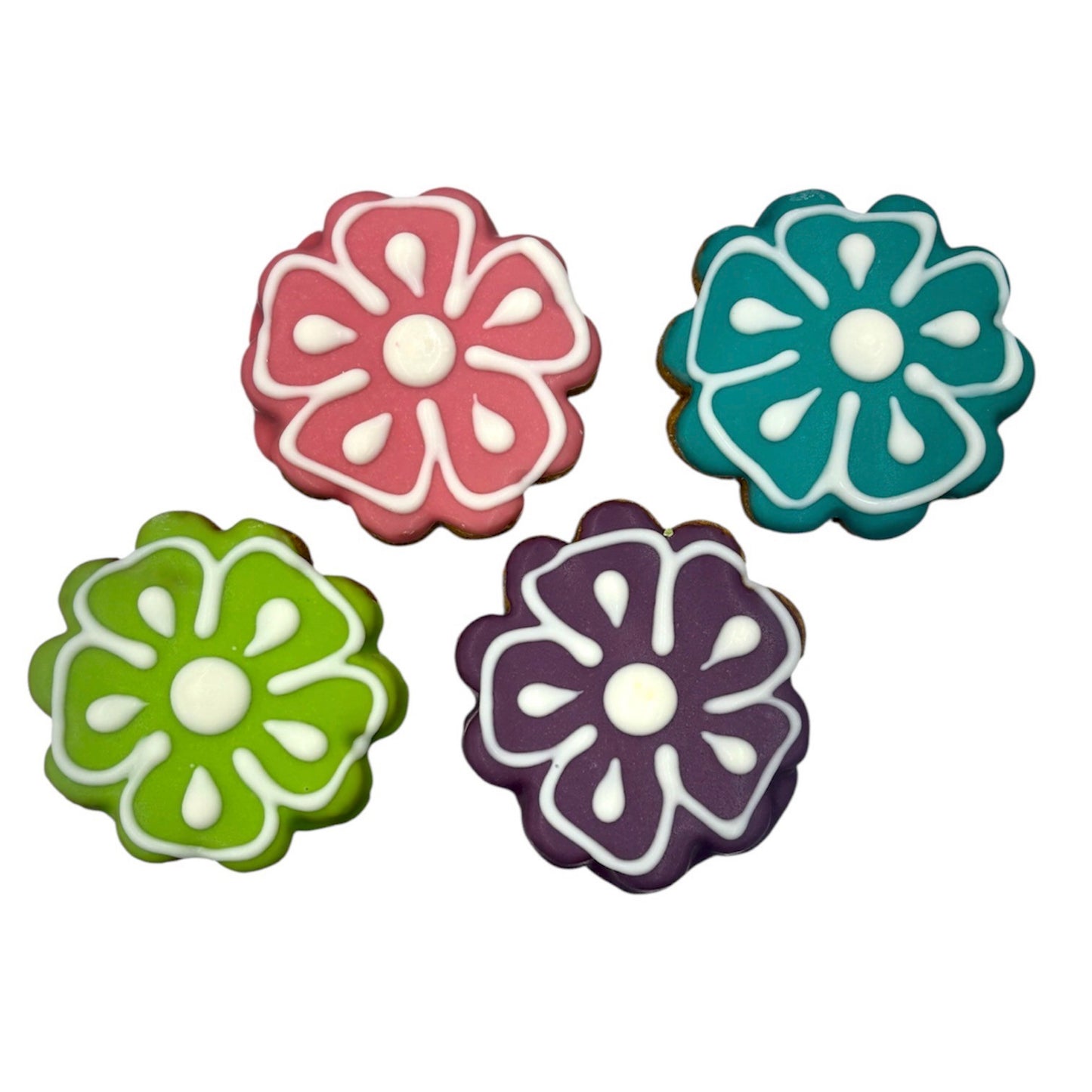 Four flower-shaped cookies with white icing, in pink, teal, green, and purple