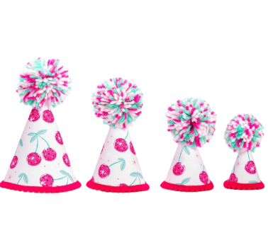 Four white party hats with pink glitter cherries and a pink and teal pom-pom on top