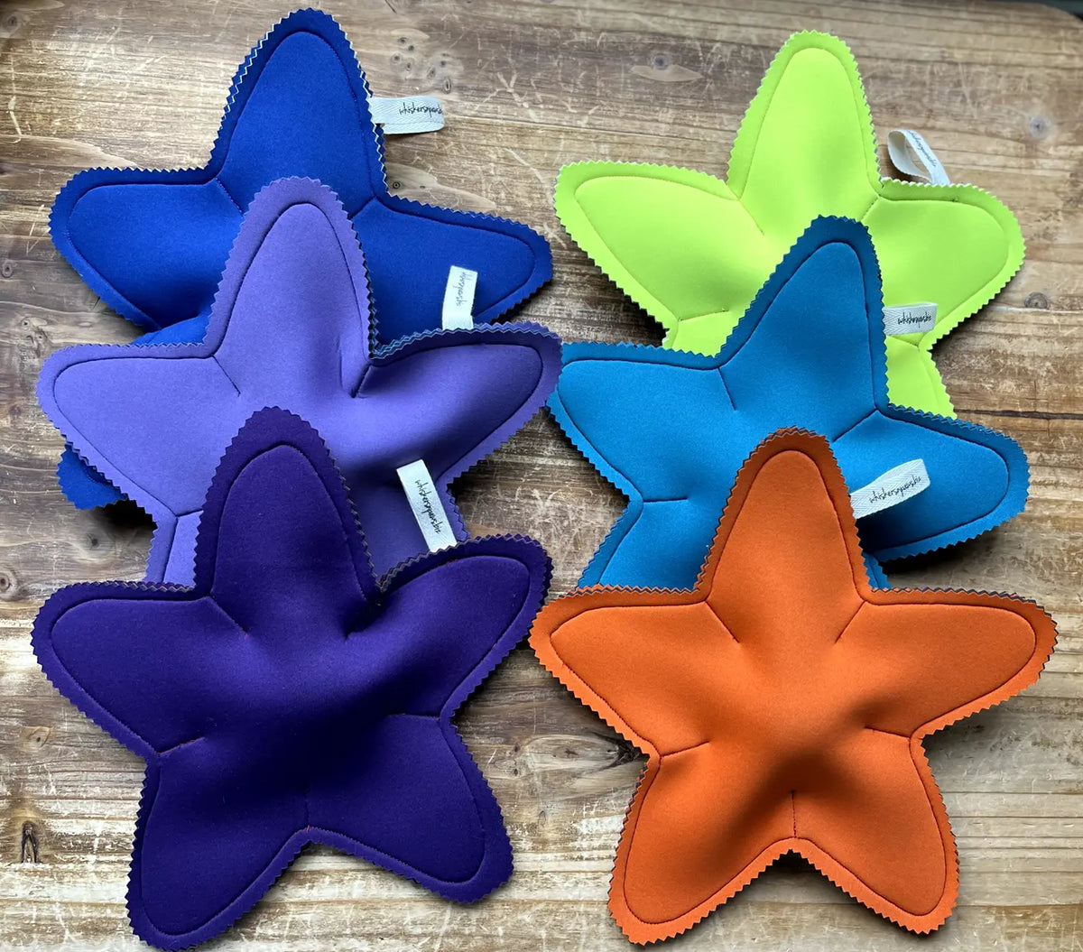 Five colorful star shaped Whiskerspash dog toys on a wooden surface