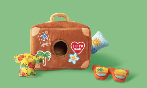 Plush suitcase with travel stickers, a Hawaiian shirt, sunglasses, and sunblock