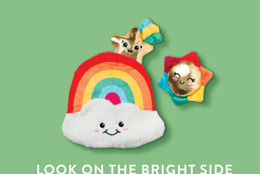 Rainbow cloud, gold star, and sun plush toys on a green background