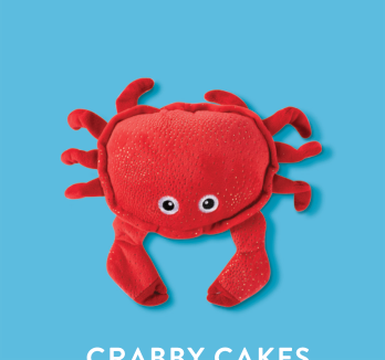 Red plush crab toy with white eyes on a blue background