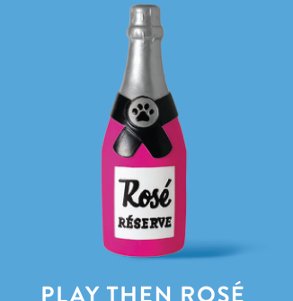 Pink champagne bottle dog toy with a black label that reads Rosé Réserve and a paw print