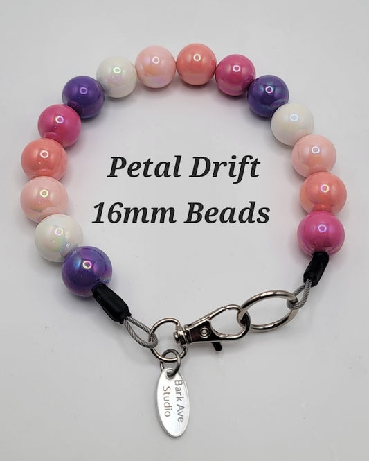 Petal Drift 16mm Beads, a collar of pink, purple, and white beads with a Bark Ave Studio tag