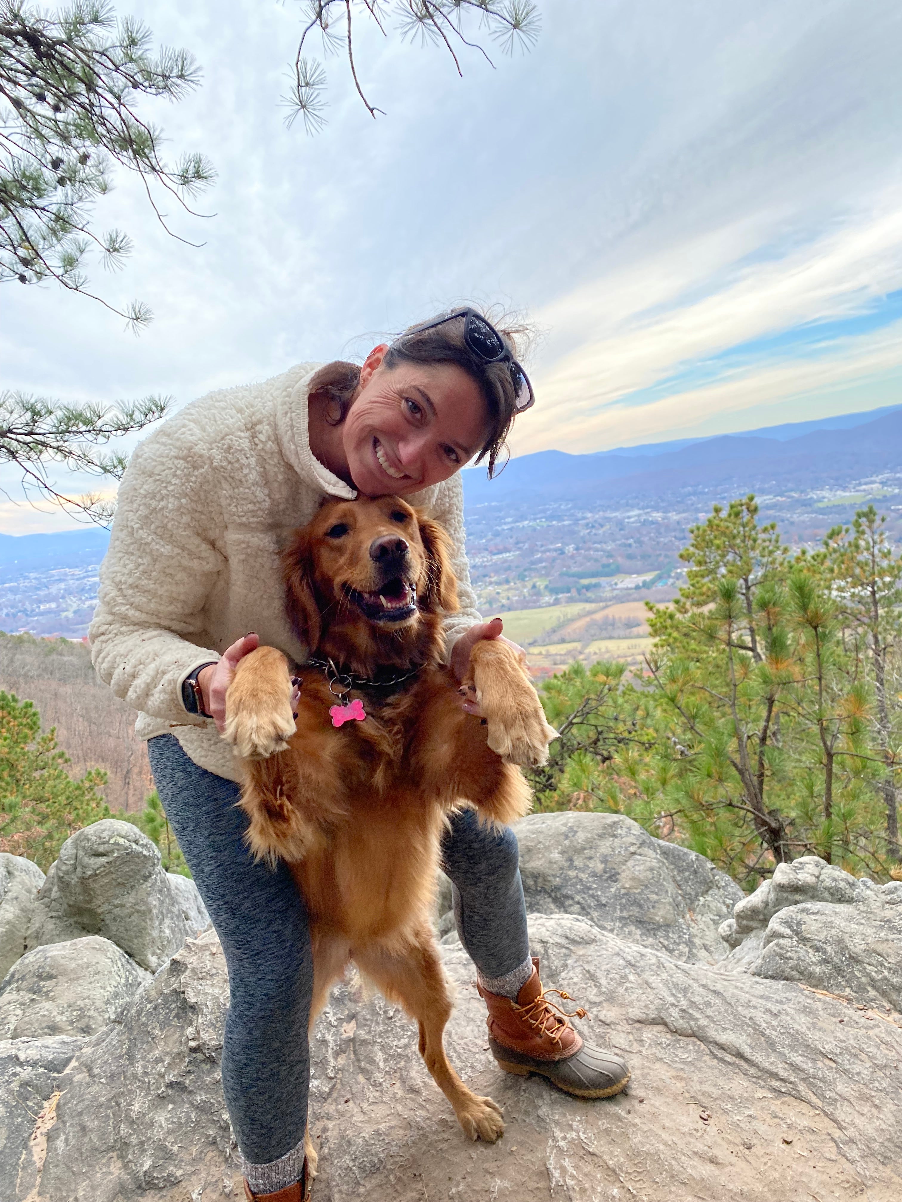 Woman holding a golden retriever on a mountain overlook