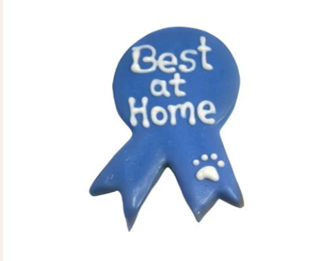 Blue ribbon shaped dog treat with white icing text Best at Home and a paw print
