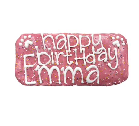 Pink dog treat with white icing that says Happy Birthday Emma and sprinkles